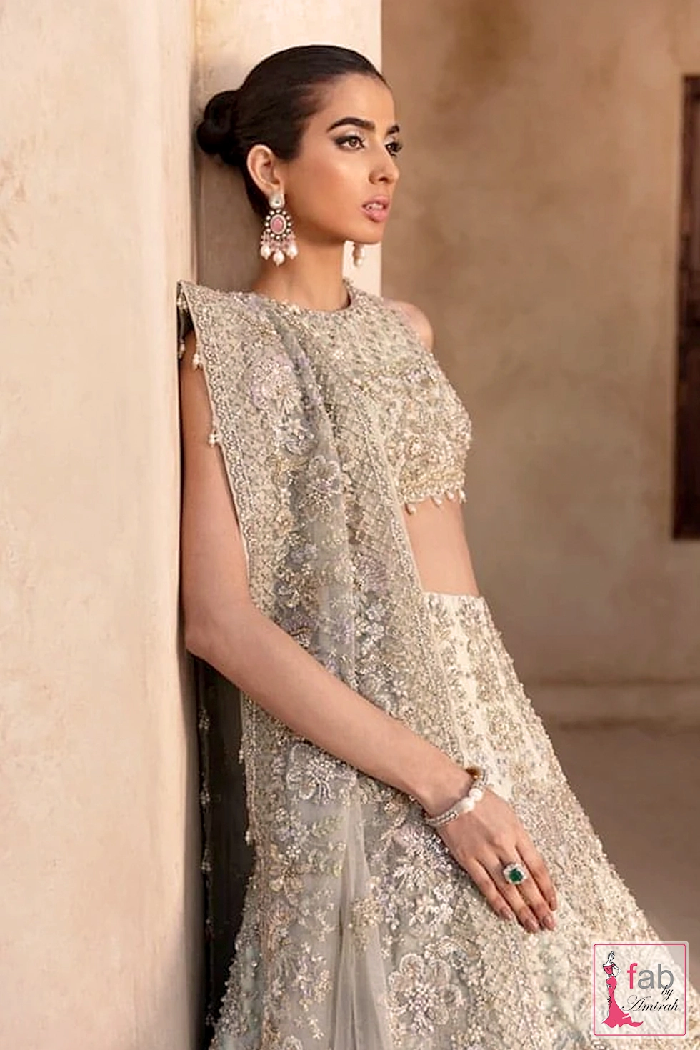 Close up of bride leaning against pillar wearing mint green lehenga blouse and dupatta