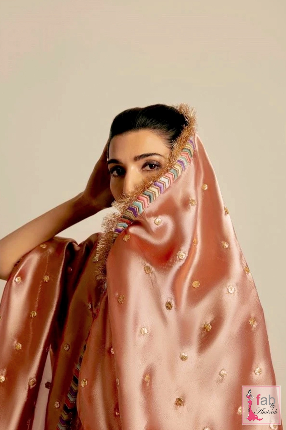 Close up view of dusty pink tissue lehenga veil framing the face with multi colored chevron borders and metallic fringe