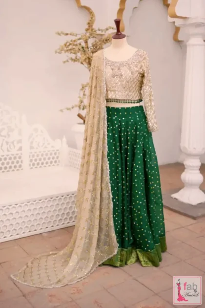 Close up of emerald green bridal lehenga set choli with hand embroidered gold grid and beaded trim
