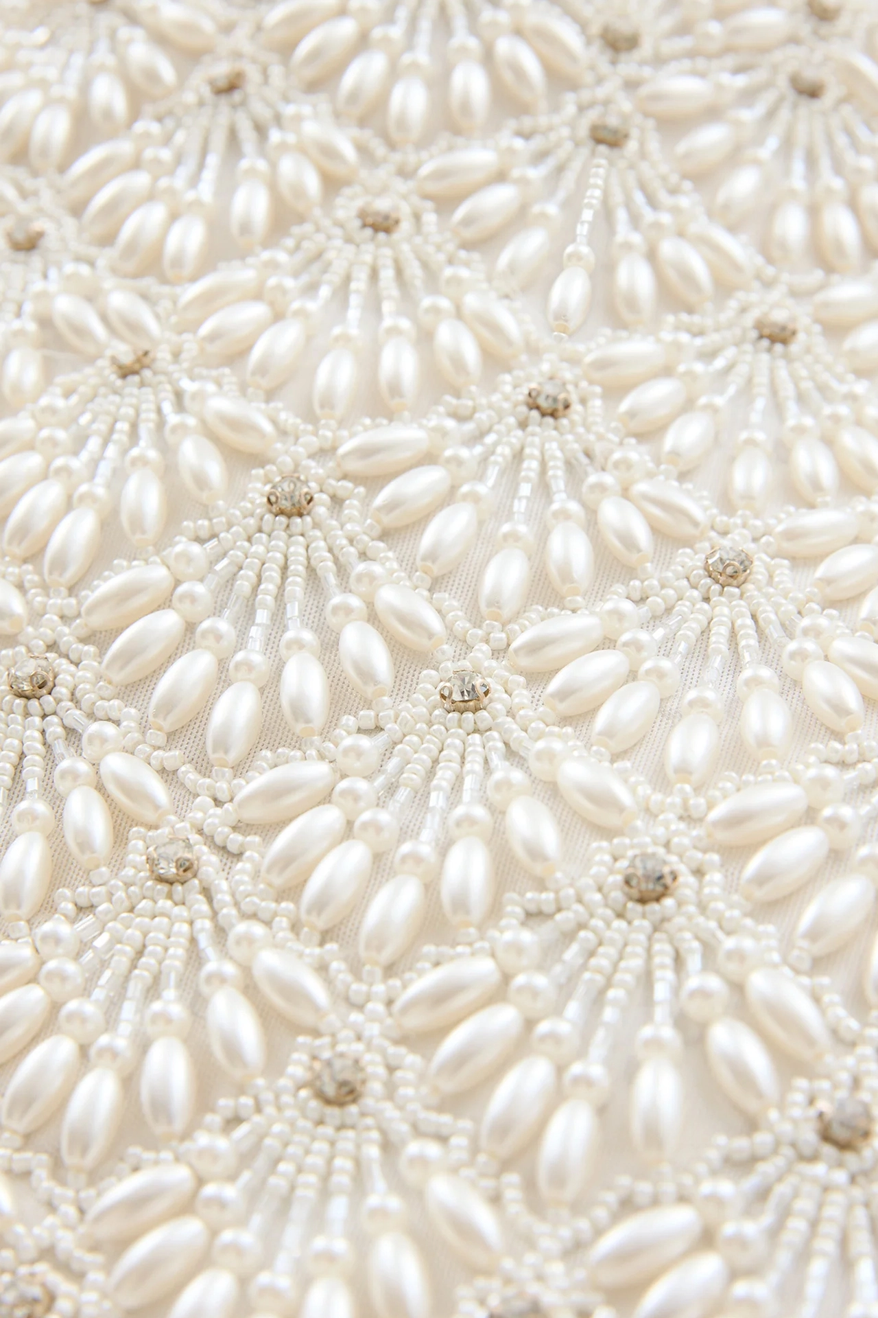 Close-up of delicate pearlescent hand embroidery on romantic bridal mini dress