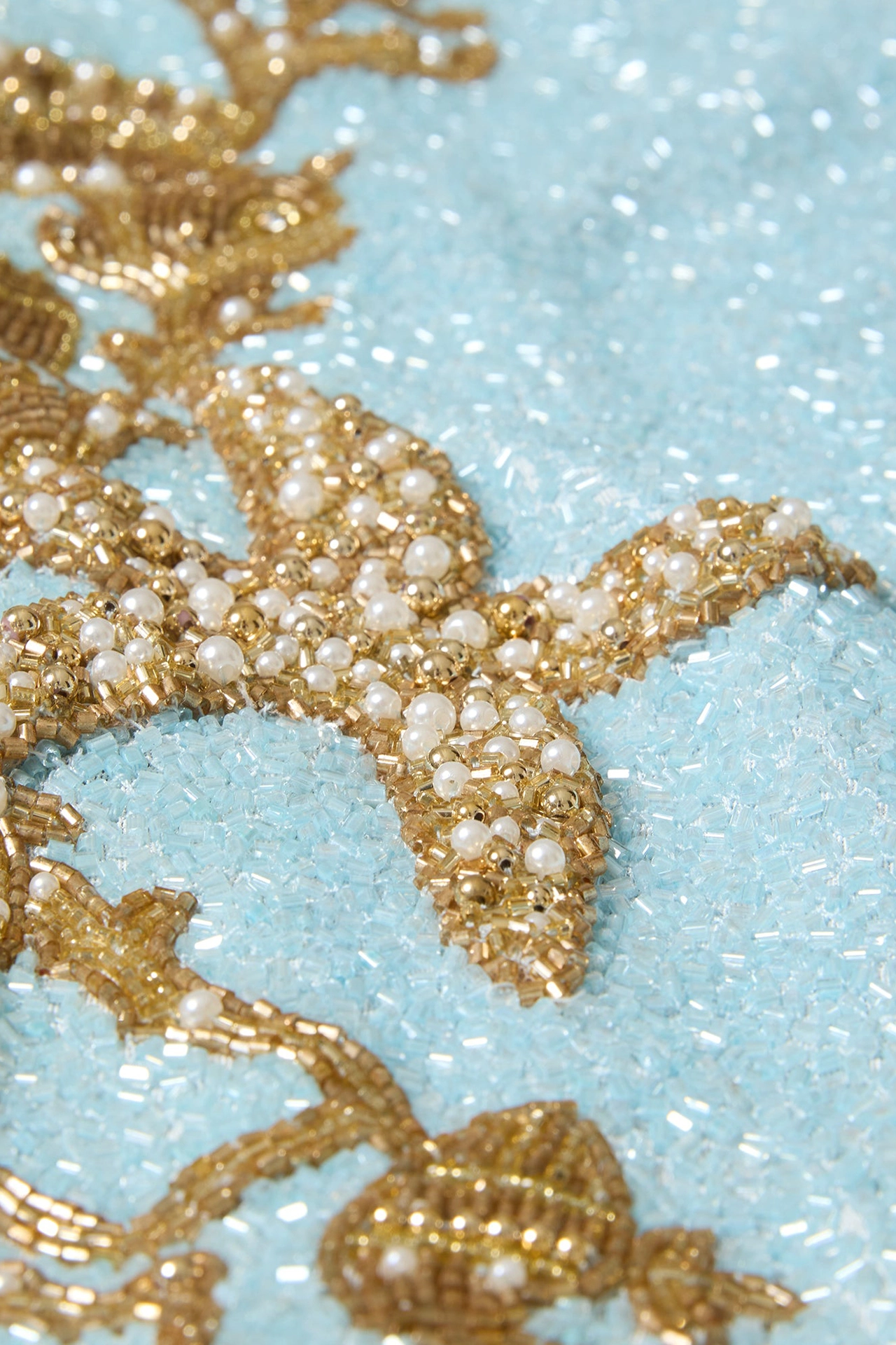 Close-up of delicate golden coral and starfish bead patterns
