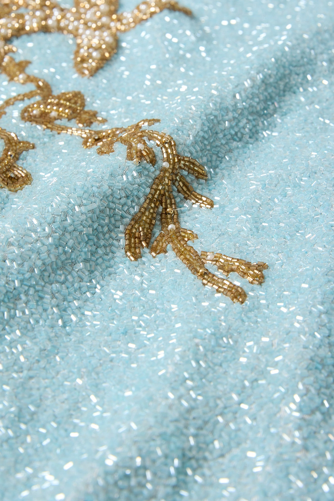 Close-up of delicate golden coral and starfish bead patterns