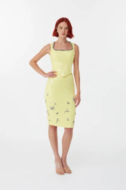 Full length look of shiny yellow party skirt styled with beige woven heels