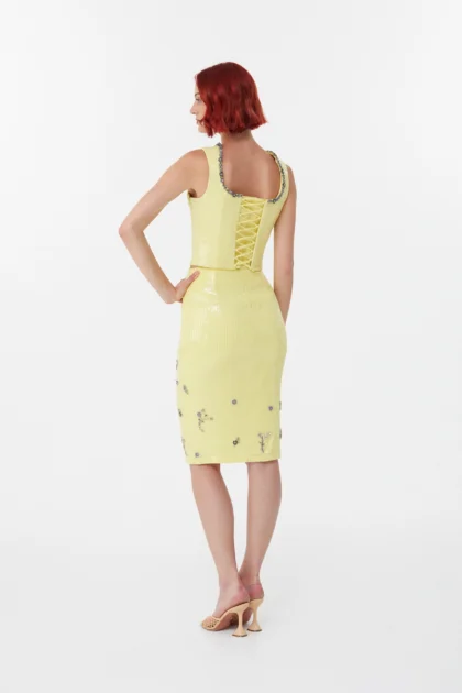 Model back view showing the lace-up corset back and shiny yellow party skirt zip look