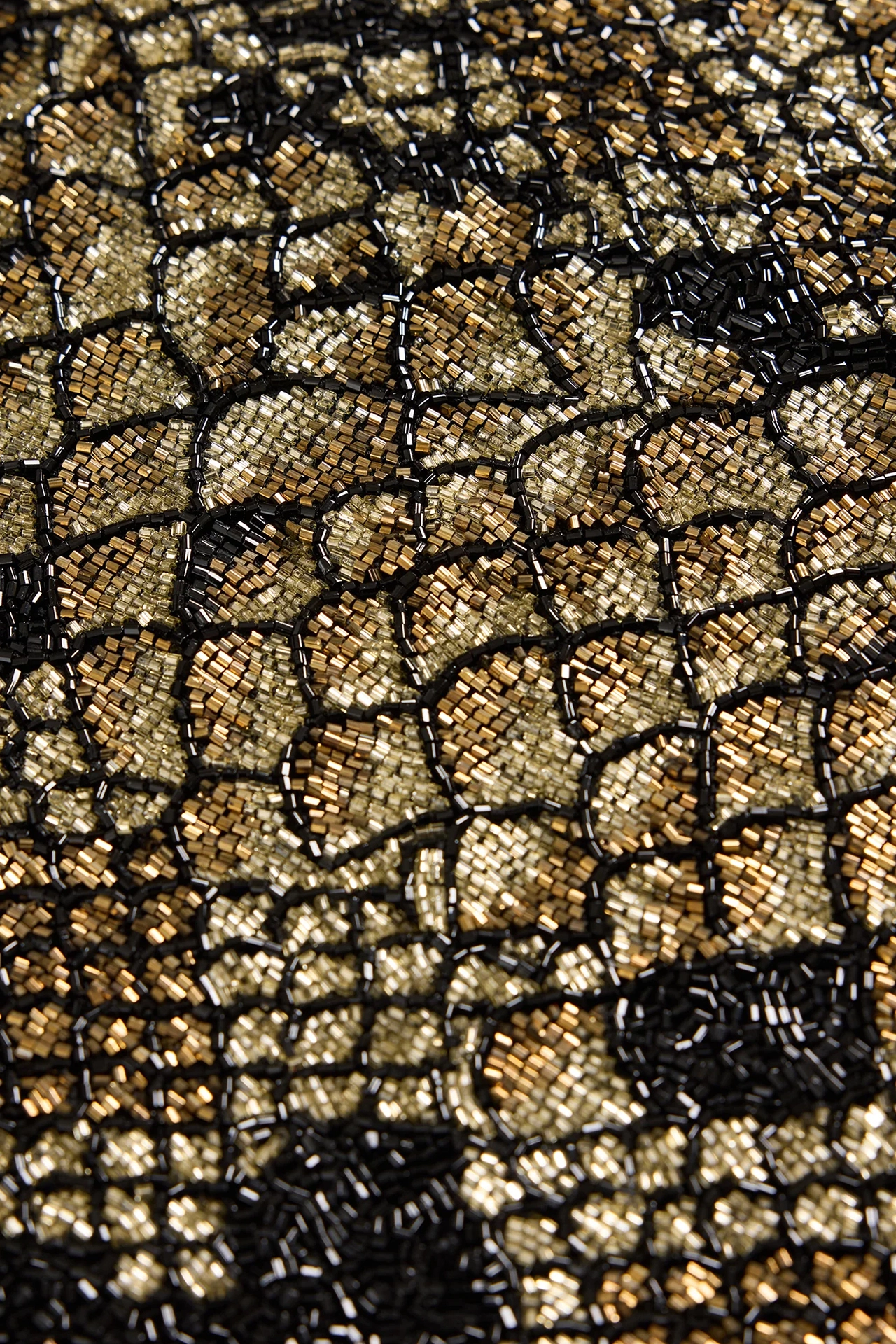 Close up view of shiny gold and black beads on snakeskin print evening dress fabric