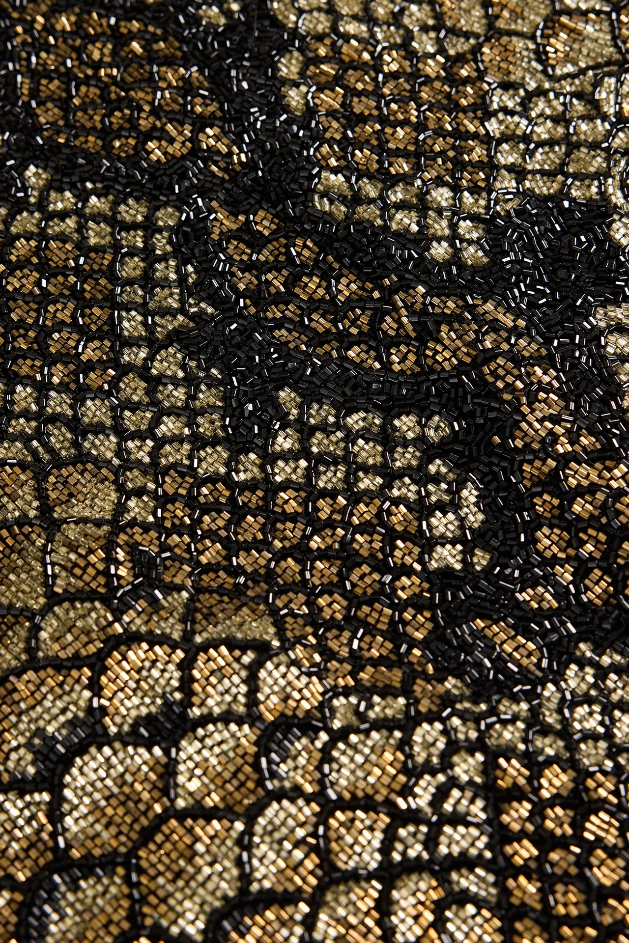 Close up view of shiny gold and black beads on snakeskin print evening dress fabric