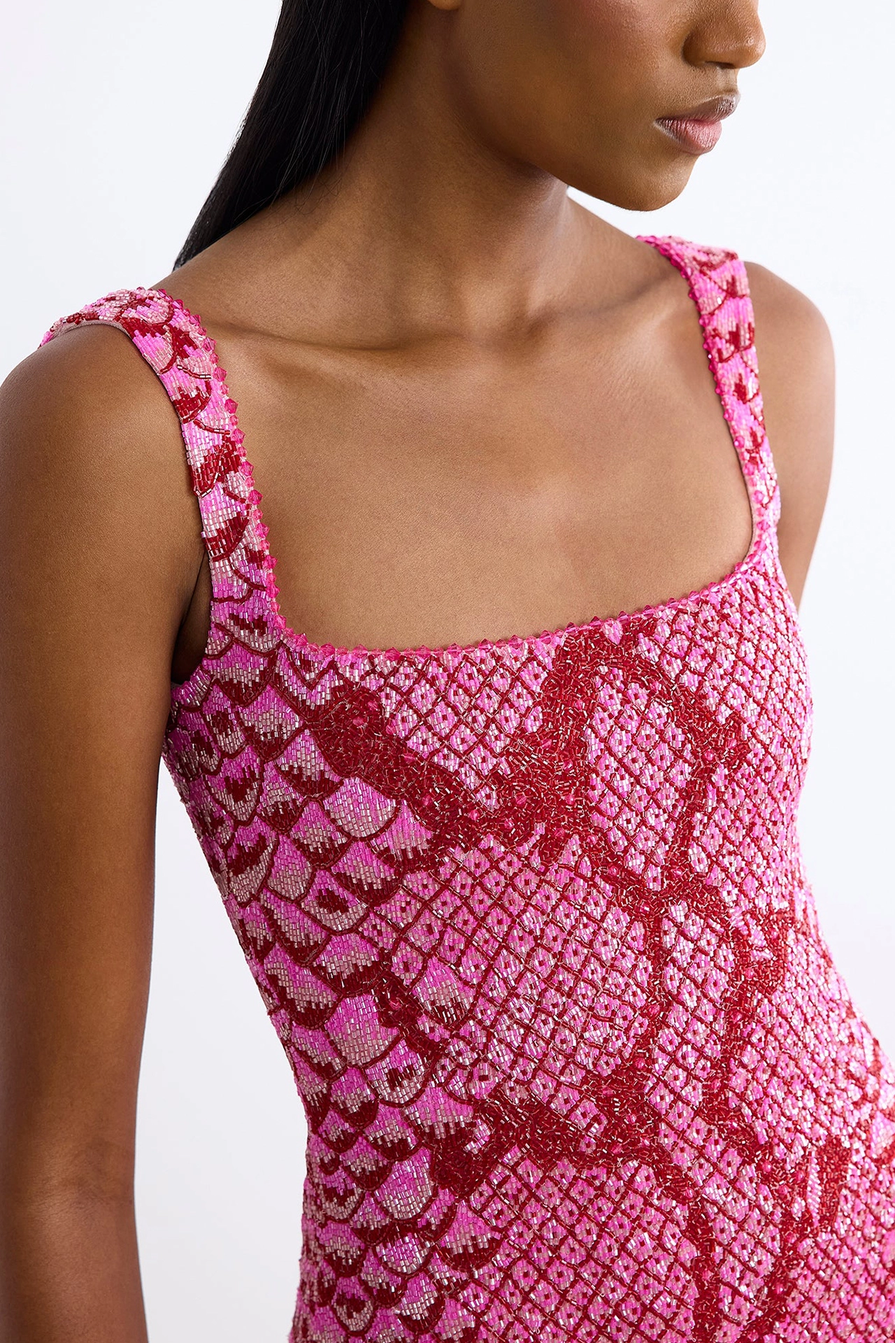 Close-up of square neck dress with beads in dark red on bright pink fabric