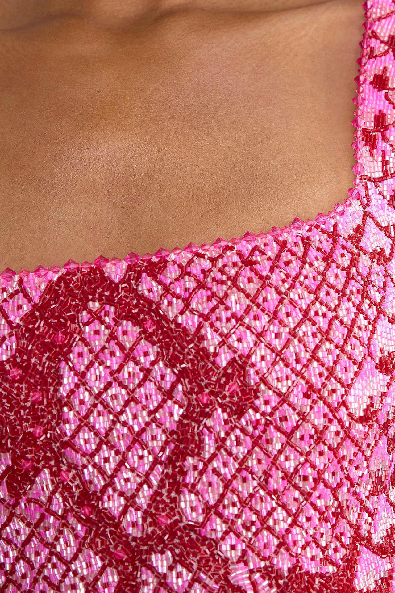 Close-up of square neck dress with beads in dark red on bright pink fabric
