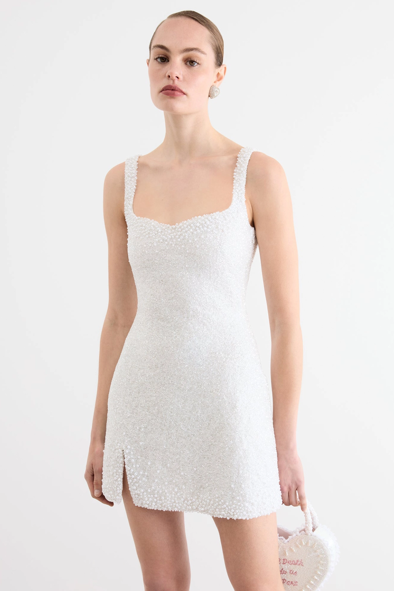 Stunning Ivory Bridal Shower Mini Dress with Pearls 1 Ivory bridal shower mini dress worn by model with sweetheart neckline and split hem next to heart bag.