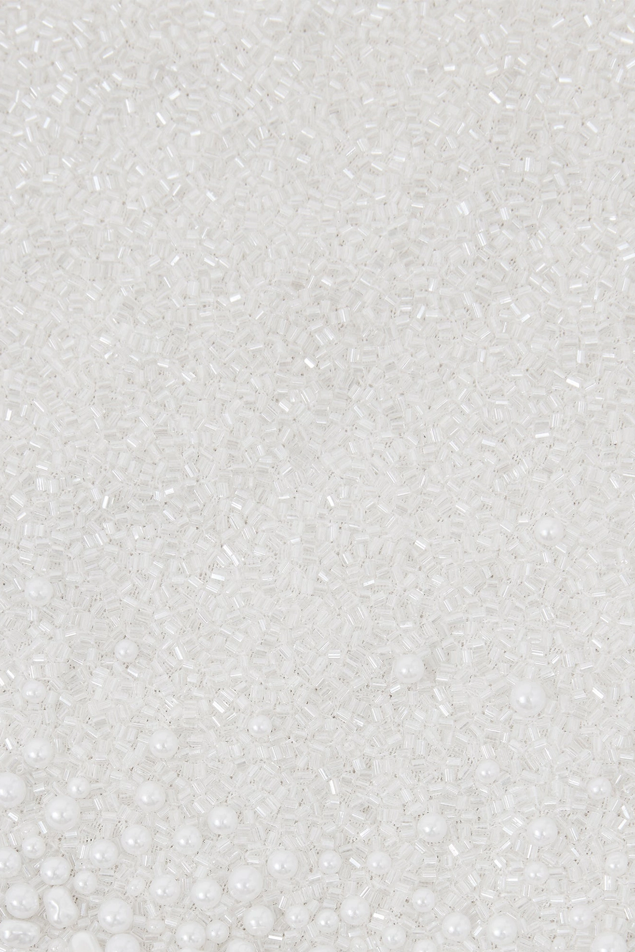 Close-up of hand-sewn pearls and mini crystals on ivory bridal shower mini dress fabric mesh. Close-up of hand-sewn pearls and mini crystals on ivory bridal shower mini dress fabric mesh.