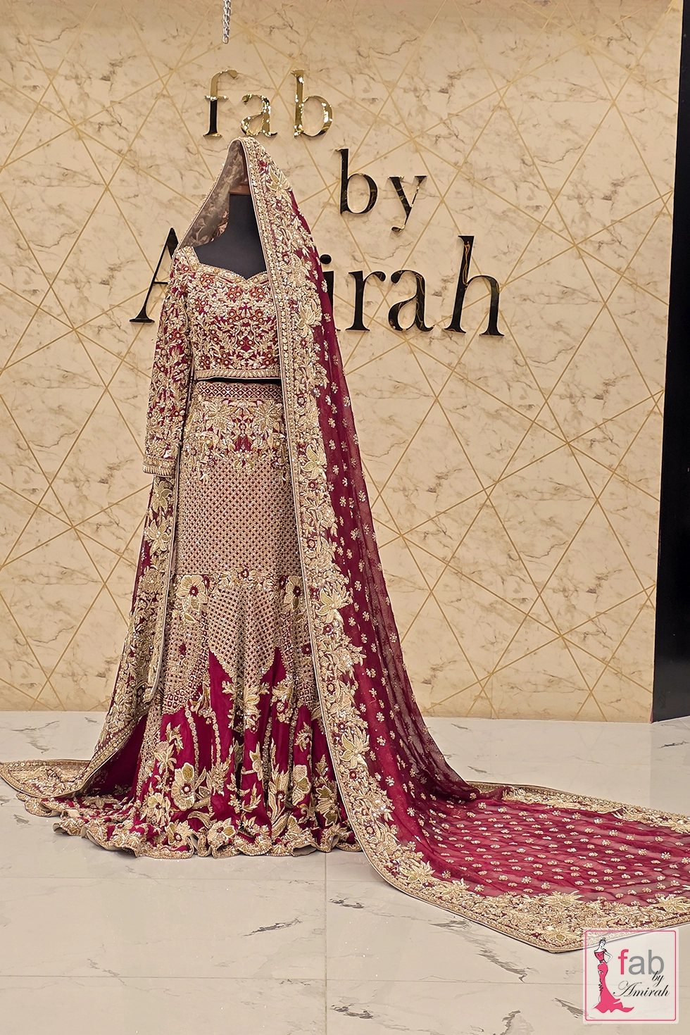 Full view of opulent maroon bridal lehenga set on mannequin display