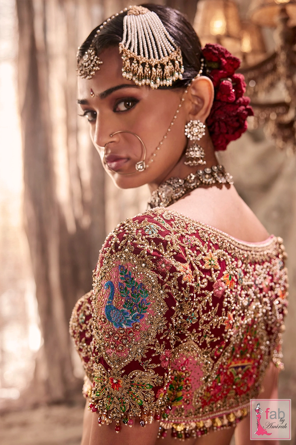 Close up side view of embroidered choli sleeve and statement bridal jewelry.