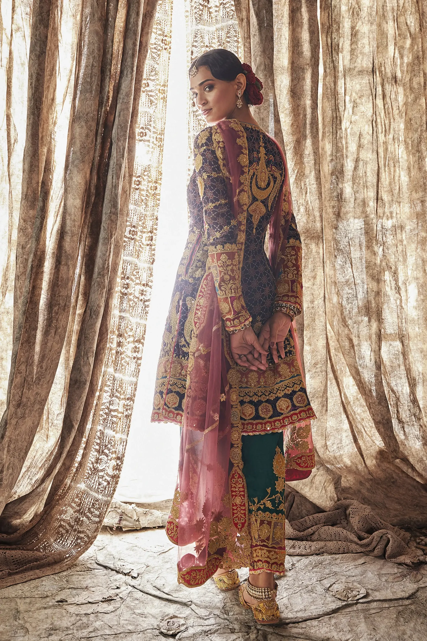 Back view of designer party wear dress showing detailed gold embroidery on neck panel and green salwar legs Back view of designer party wear dress showing detailed gold embroidery on neck panel and green salwar legs