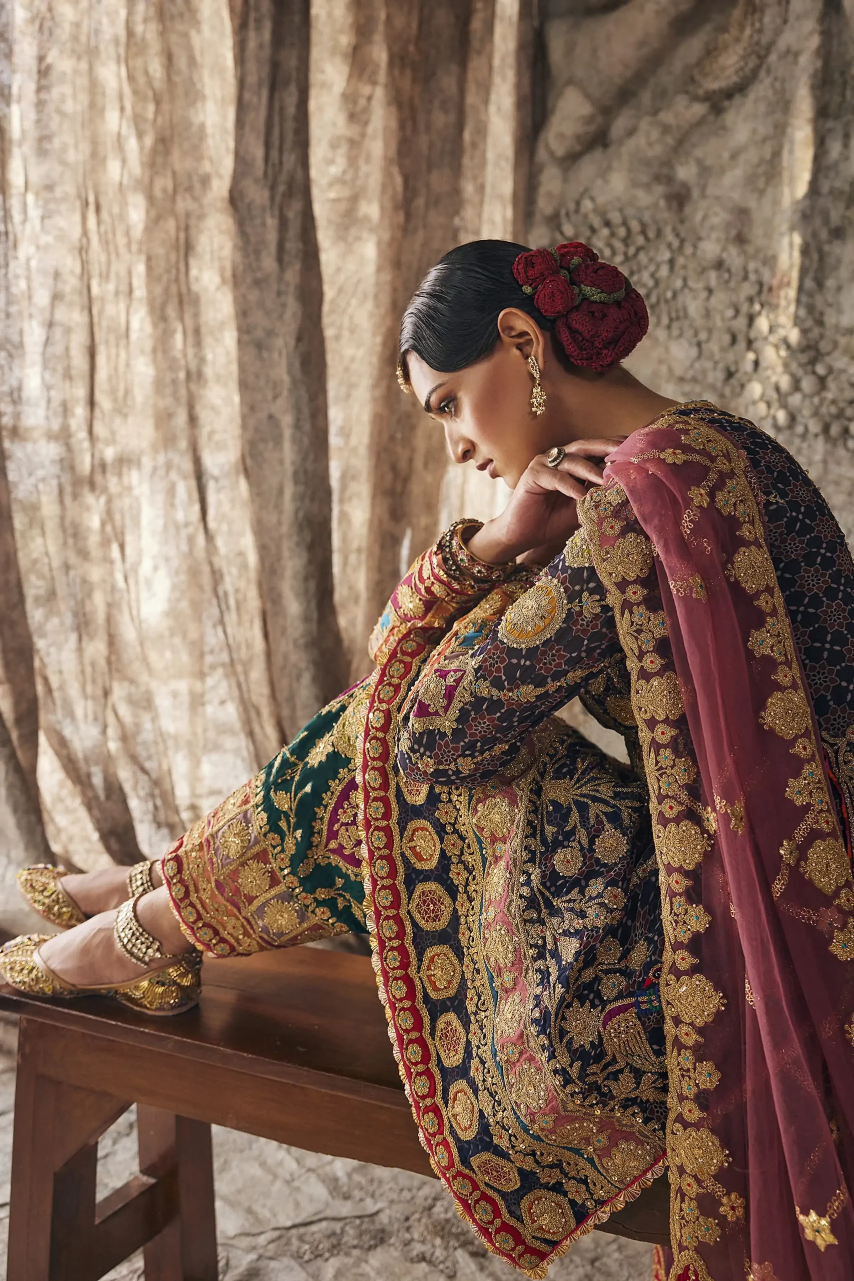 Seated profile view of designer party wear dress highlighting intricate mirrorwork along side slits and borders. Seated profile view of designer party wear dress highlighting intricate mirrorwork along side slits and borders.