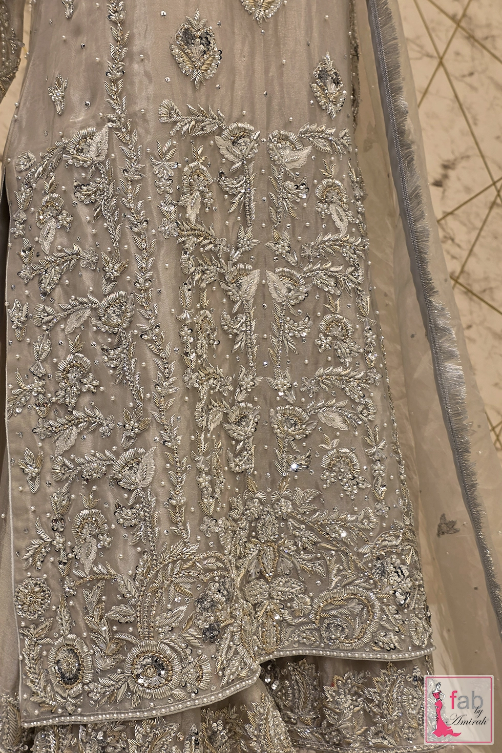 Close up view of mid section hand embroidery on silver tunic