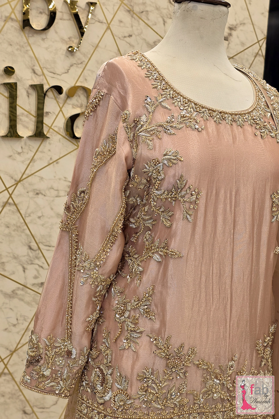 Detail view of the round neckline, full length embellished sleeves, and intricate floral embroidery motifs on the upper kameez