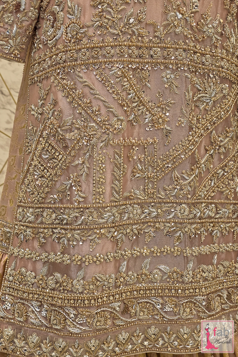 Close up detail of heavy metallic thread embroidery, zari work, sequins, and pearl hand embellishments along the hemline