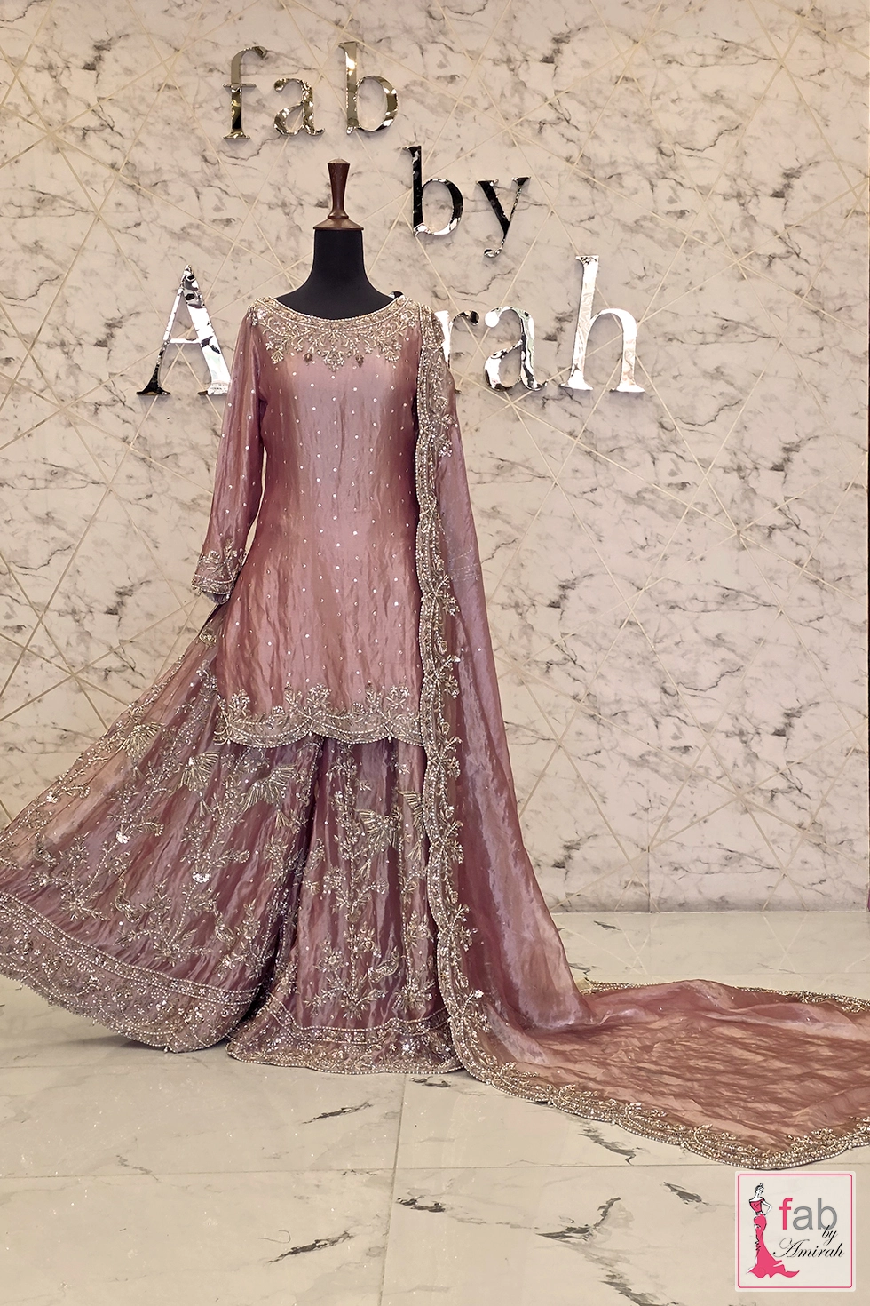Full front display of dusty pink sharara suit with trailing organza dupatta.