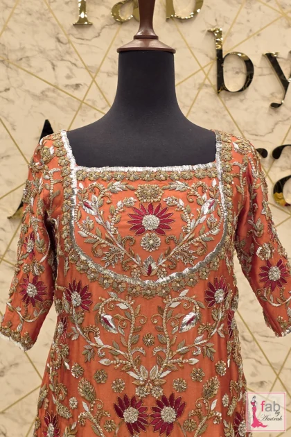 Close up of side slit embroidery detail on rust silk shirt