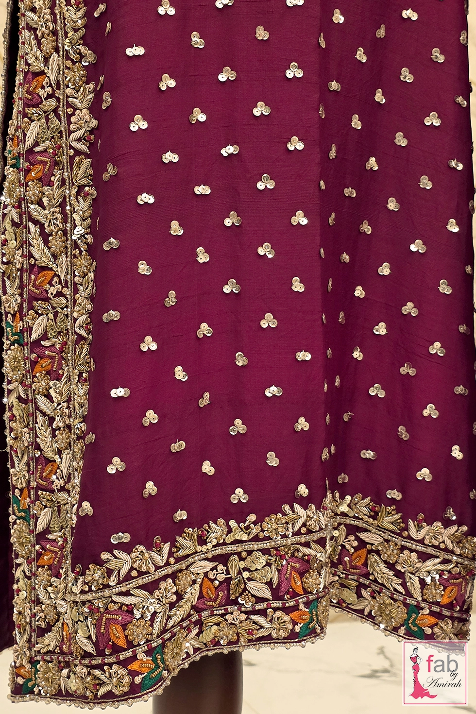 Detailed view of hand embroidered shirt hemline and scattered sequin sprays