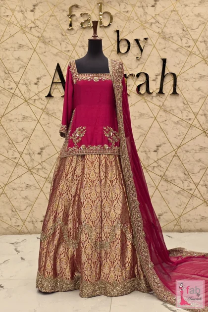 Full view of a magenta bridal lehenga with gold hand embroidery