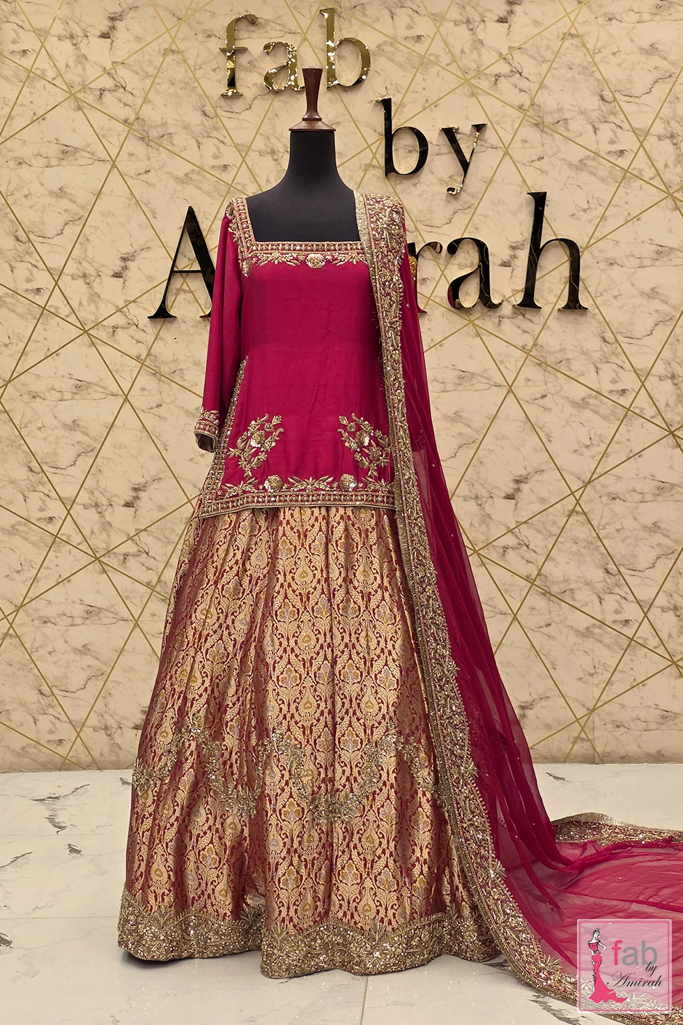 Full view of a magenta bridal lehenga with gold hand embroidery