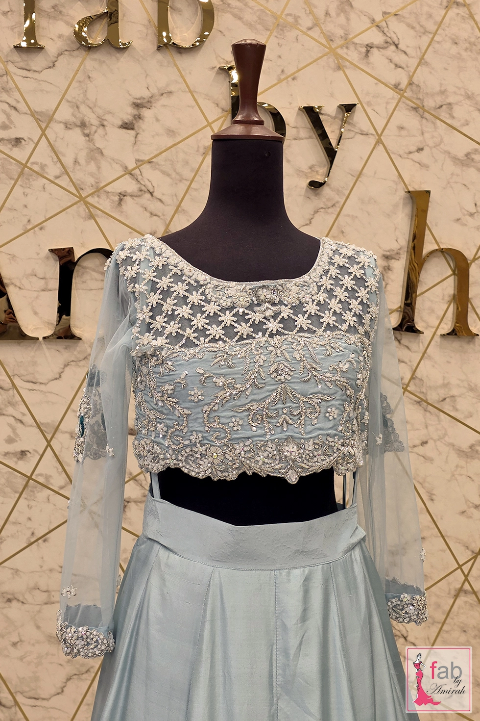 Mid shot focus on the cropped blouse waist line and sheer embellished sleeves