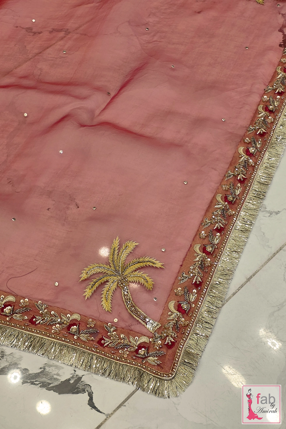 Border detail of magenta net dupatta featuring gold fringe trimming and palm motif
