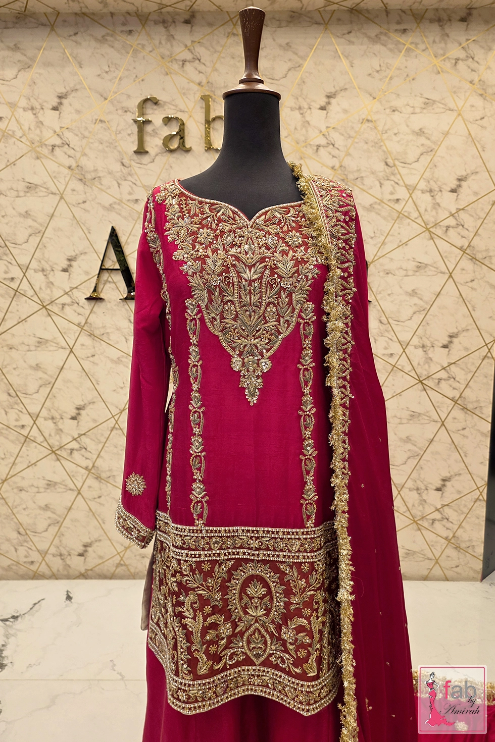 Medium close up of embroidered neckline and lower hem detailing on magenta tunic.