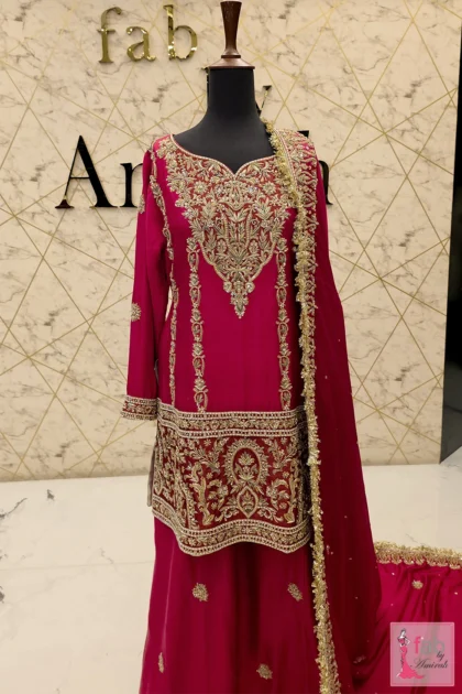 Front view of a magenta bridal sharara featuring heavy gold zardozi neck embroidery