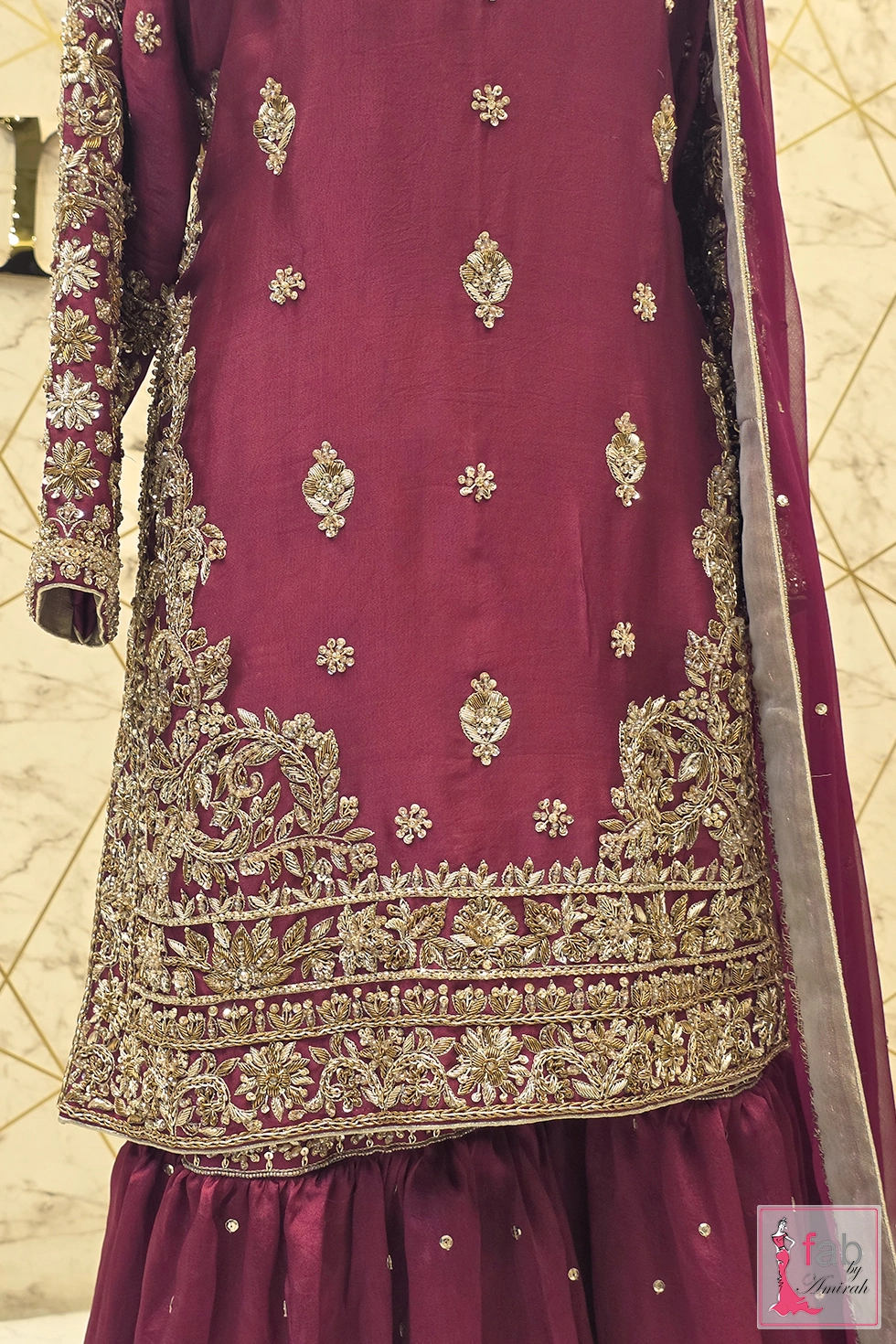Front detail of short magenta shirt with heavy hem embroidery