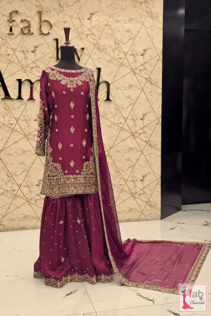 Deep magenta gharara dress with gold zardozi embroidery displayed on mannequin