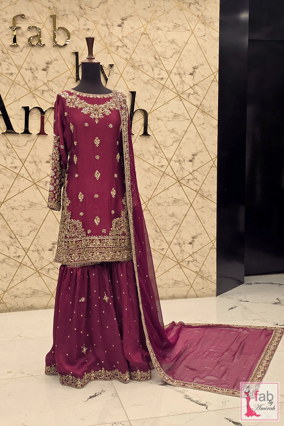 Deep magenta gharara dress with gold zardozi embroidery displayed on mannequin