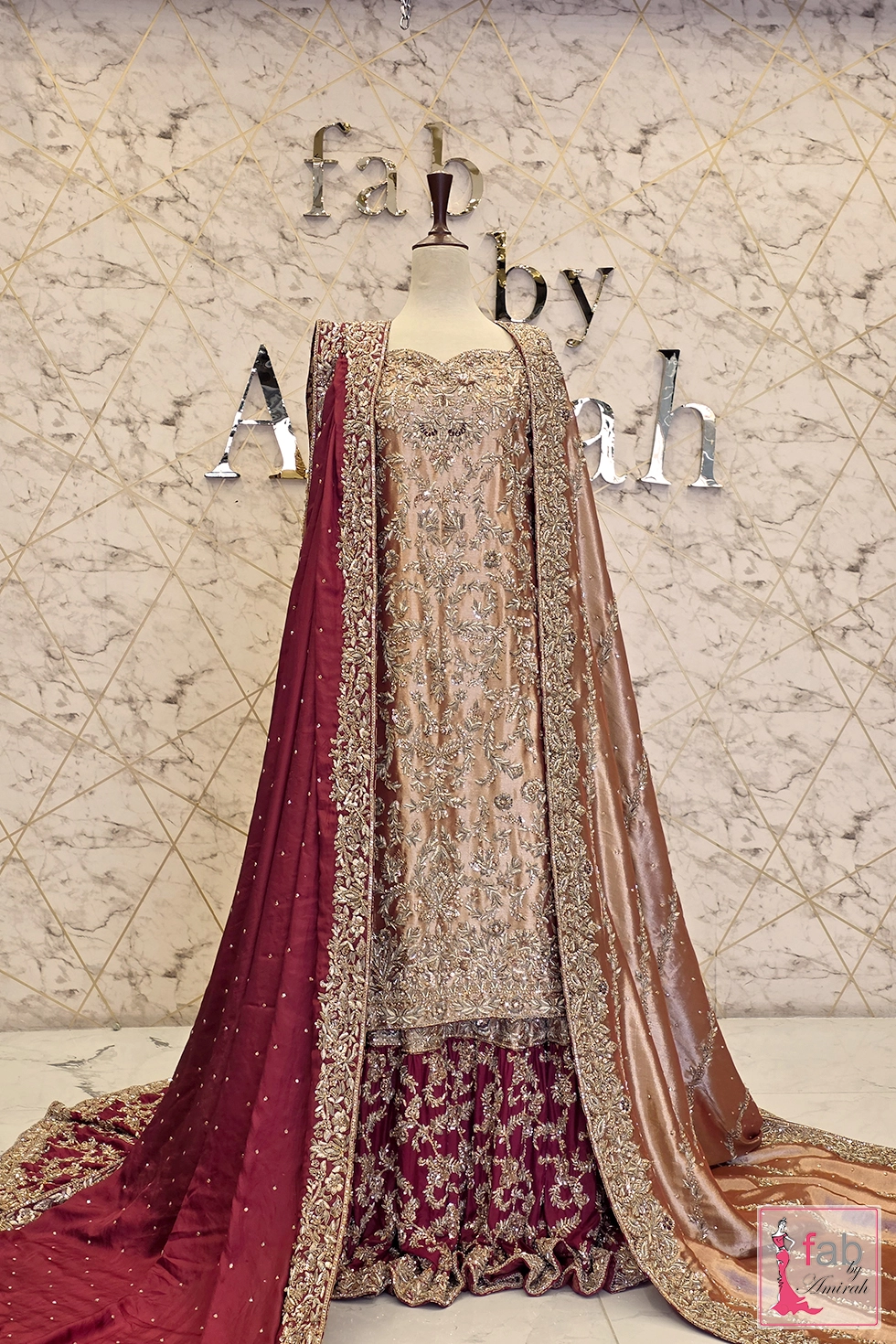 Full front view of champagne gold and maroon designer farshi lehenga suit on mannequin.