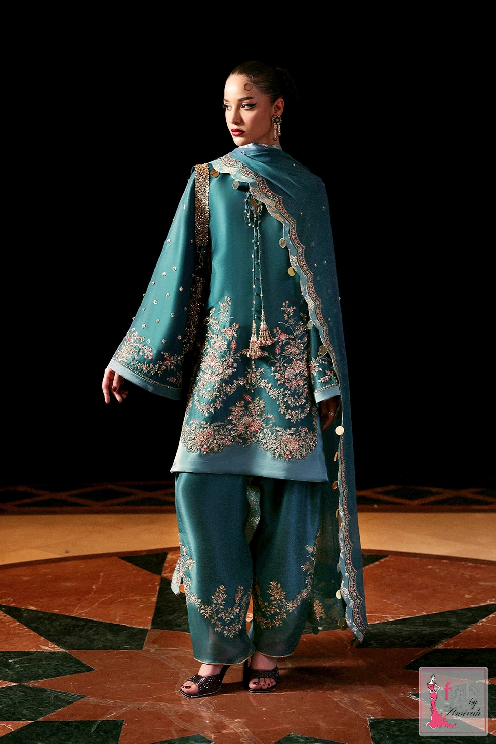Full length view of model wearing teal embroidered short shirt with flared shalwar. Full length view of model wearing teal embroidered short shirt with flared shalwar.